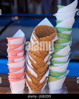three stacks of empty sugar vivid multi-colored wafer cone cups for ice cream. pink, green and chocolate Stock Photo