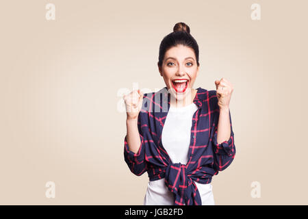 surprised portrait of happy winner ecstatic young woman with casual style having shocked look, exclaiming, keeping mouth wide open and fists clenched  Stock Photo