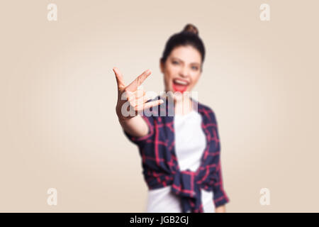 Rock sign. Happy funny toothy smiley young woman showing Rock sign with fingers. studio shot on beige background. focus on fingers. Stock Photo