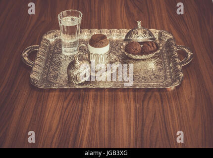 Turkish coffee served with water and cookies on a traditional copper serving set Stock Photo