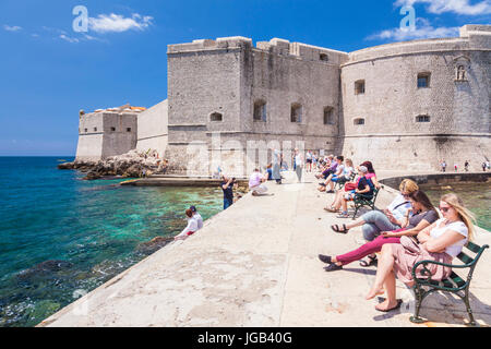 Croatia Dubrovnik Croatia Dalmatian coast tourists sitting on the sea wall Arsenal St John Fort dubrovnik old harbour city walls old town Dubrovnik Stock Photo