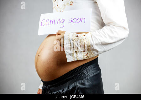 Pregnant woman holding sign regarding her baby: coming soon Stock Photo