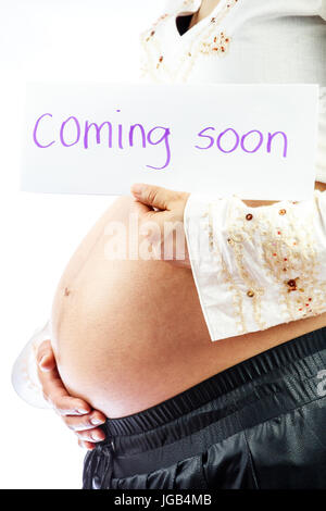 Pregnant woman holding sign regarding her baby: coming soon Stock Photo