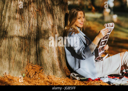 Young pregnant woman looking fetus ultrasound images in the autumn park Stock Photo