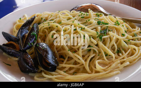 Spaghetti seafood with mussels and fresh green onions closeup.Seafood Pasta with cooked mussels in shell, served on a white dish with spoon. Stock Photo