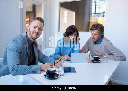 Smiling young professional with colleagues working in the background Stock Photo