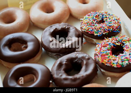 Multicolored sprinkles on chocolate donuts from Krispy Kreme Stock Photo