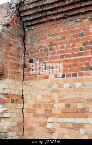 Close-up view of cracked old building brick wall with eroded bricks on top, background concept Stock Photo