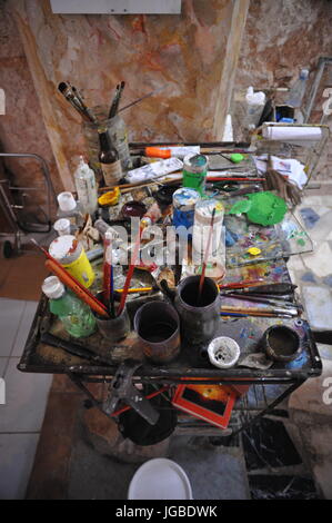 mess artists workstation including paints materials and brushes on a mixing table creative Stock Photo