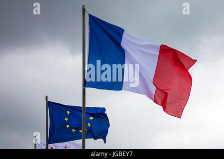 French and EU flag against an overcast sky Stock Photo