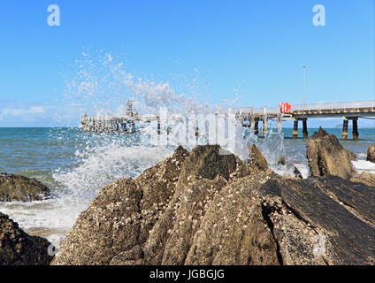 Palm Cove northern end, wave splashing on the rocks and obscuring the view of the jetty Stock Photo