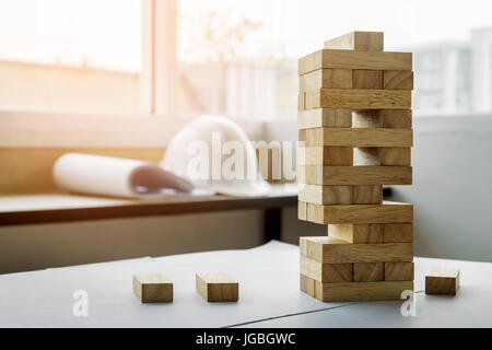 the blocks wood tower game with architectural engineer plans or blue prints compasses ,pencils and ruler on wooden table, plan and building concept. Stock Photo