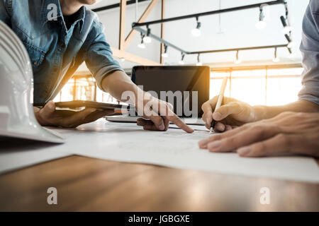 Two Architects engineer discussing  data working and tablet, laptop with blueprint - Closeup on hands and project print. Stock Photo