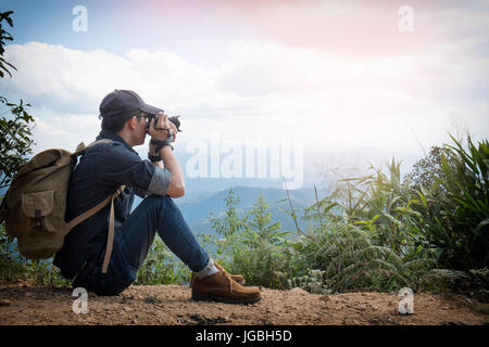 Young professional travrler man with camera shooting outdoor, fantastic mountain landscape. Stock Photo
