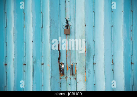 Mettalic lock without the key on the blue vintage door,Residential mettalic folding door with blue locking device installed Stock Photo