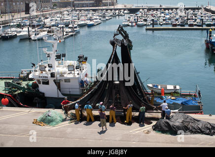 Fishermen inspecting nets on fishing boat in Santoña harbour, Cantabria, Spain Stock Photo
