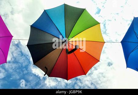 Rainbow color umbrella on the blue cloudy sky background in Gdynia, Poland Stock Photo