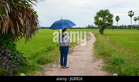 An Giang, Vietnam - Aug 7, 2016. A woman with umbrella on countryside road in Mekong Delta, Vietnam. The Mekong Delta is also Vietnam's most important Stock Photo