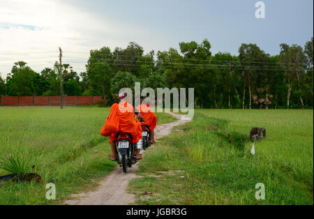 An Giang, Vietnam - Aug 7, 2016. Khmer monks riding scooter on rural road in Mekong Delta, Vietnam. Khmer pagodas and villages surrounded by rice padd Stock Photo