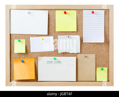 A cork pinboard, isolated on white, with a variety of pushpins sticky notes, cards and pieces of paper, left blank to provide copy space for messages. Stock Photo