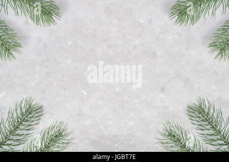 A background texture of artifical snow with ice fragments, framed by Christmas tree branches positioned in the corners. Stock Photo