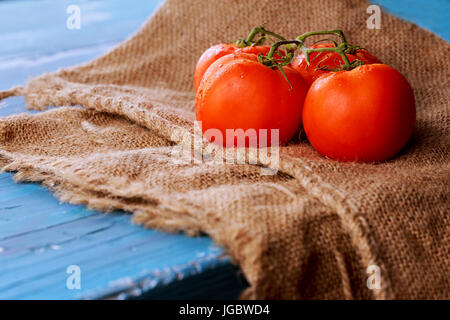 Tomatoes on vine with clipping path on cutting board , blue vintage wooden background, healthy lifestyle, cooking and market concept