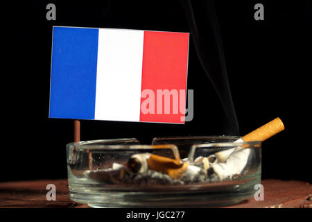 French flag with burning cigarette in ashtray isolated on black background Stock Photo