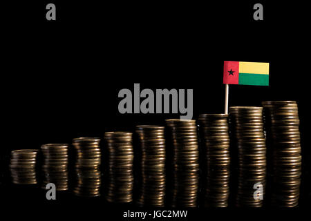 Guinea Bissau flag with lot of coins isolated on black background Stock Photo
