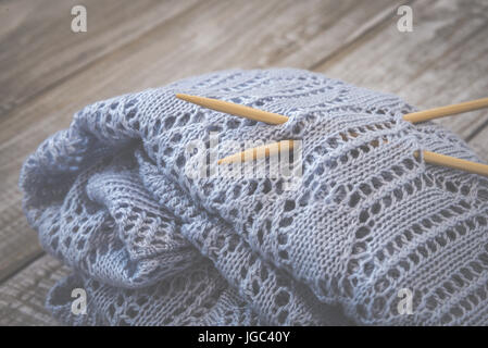 Detail of woven handicraft knit woolen design texture and knitting bamboo needle. Rustic wooden background Stock Photo