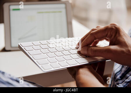 closeup of a young caucasian man in pajamas typing in a computer keyboard Stock Photo
