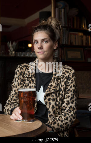 A modern young woman drinking real ale in a London pub Stock Photo