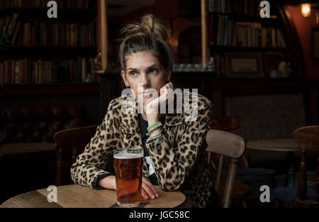 A modern young woman drinking real ale in a London pub Stock Photo