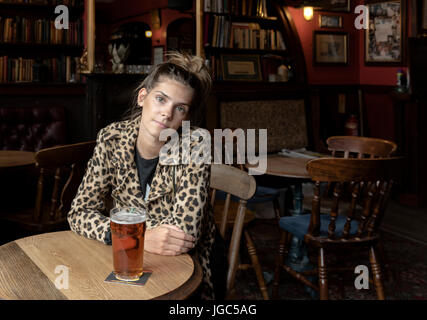 A modern young woman drinking real ale in a London pub Stock Photo