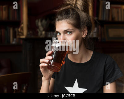 A modern young woman drinking real ale in a London pub Stock Photo