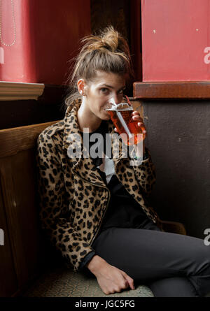 A modern young woman drinking real ale in a London pub Stock Photo