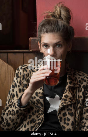 A modern young woman drinking real ale in a London pub Stock Photo