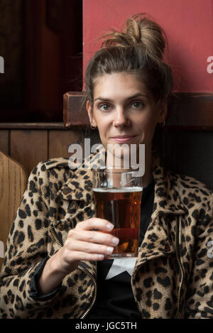 A modern young woman drinking real ale in a London pub Stock Photo