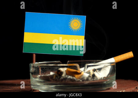 Rwanda flag with burning cigarette in ashtray isolated on black background Stock Photo