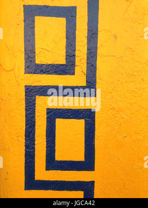Colorful bright yellow and blue geometric pattern painted on the wall of a building in a close up view of the surface Stock Photo