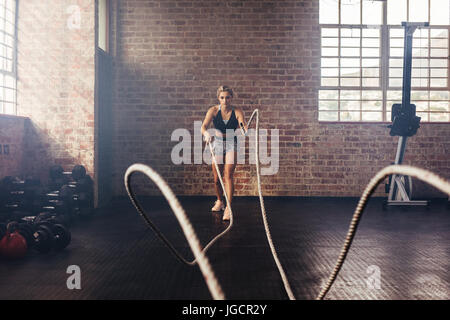 Young woman doing strength training using heavy ropes at the gym. Athlete  moving the ropes in wave motion as part of strength training Stock Photo -  Alamy