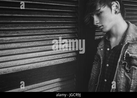 Sad teenage boy leaning against a wall Stock Photo