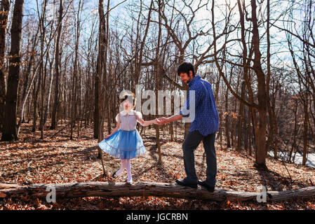 Father and daughter standing on a tree trunk in the forest Stock Photo