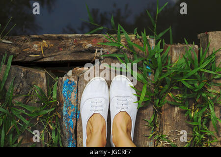 Close-up of a woman's feet standing on a wooden bridge Stock Photo