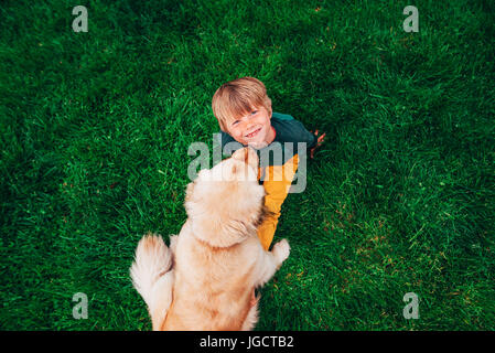 Overhead view of a boy playing with his golden retriever dog Stock Photo