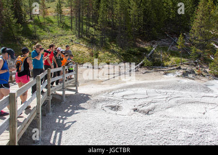 Tourists are taking pictures of a geyser from the boardwalk at Artists Paintpots in Yellowstone National Park Stock Photo