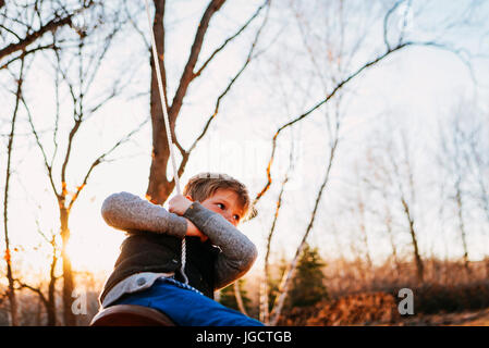 Boy swinging on a rope swing Stock Photo