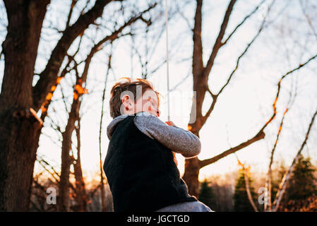 Boy swinging on a rope swing Stock Photo