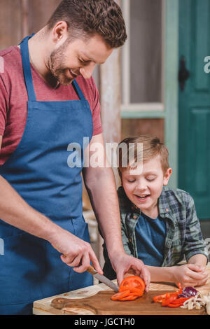 Smiling father and son cutting fresh vegetables at backyard, dad and son cooking concept Stock Photo