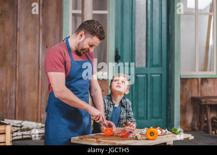 Smiling father and son cutting fresh vegetables at backyard, dad and son cooking concept Stock Photo