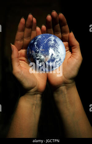 open female hand holding and protecting the planet earth Stock Photo